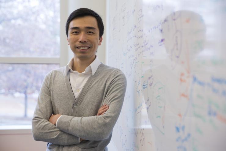 Polo Chau standing in front of a white board with equations on it.