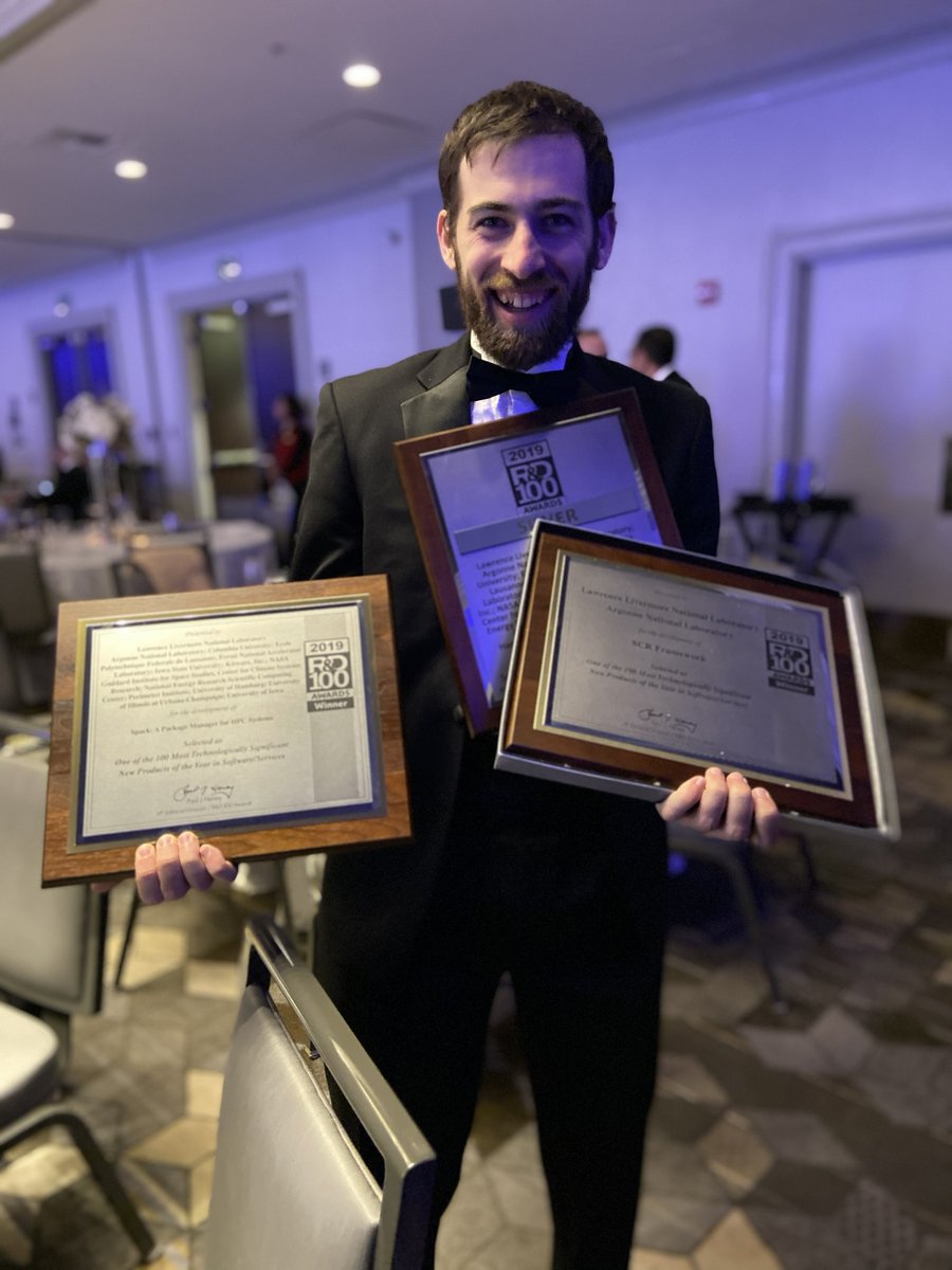 Greg holding three award plaques