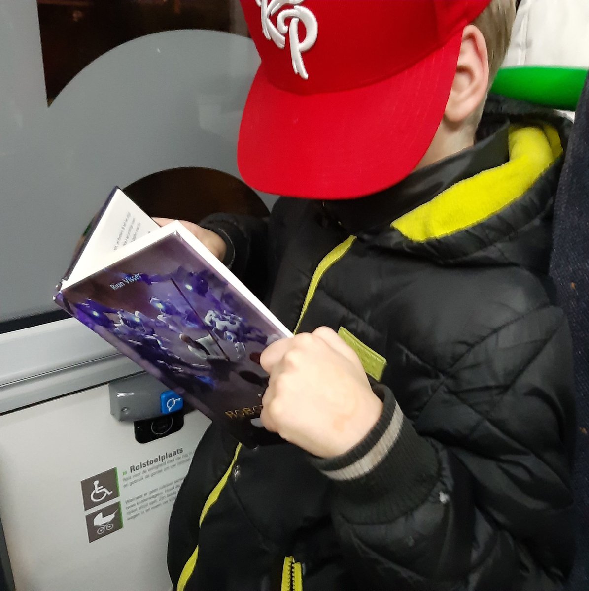 RianVisser's tweet photo. Gespot in bus 7 in Dordrecht. Bibliothecaresse zag jongen helemaal verdiept in Robotoorlog Boek 1, Geheime kracht. Ze mocht foto maken (pet over t hoofd) en ik mocht hem plaatsen. Gaaf toch als kinderen zelfs in de bus lezen?  https://t.co/moJ948GYNP #kinderboek #ontlezing https://t.co/CdgkZbKxia