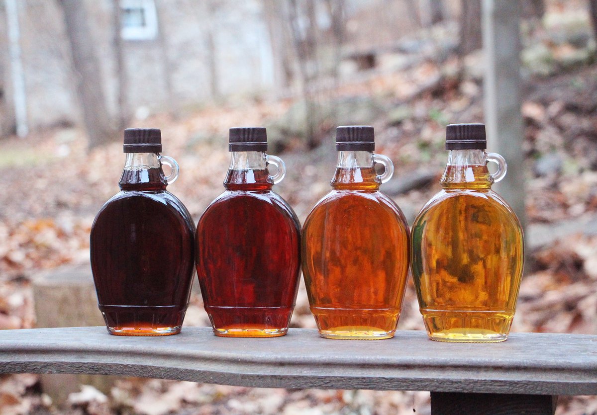 Four bottles of different coloured  Maple Syrup in a line 