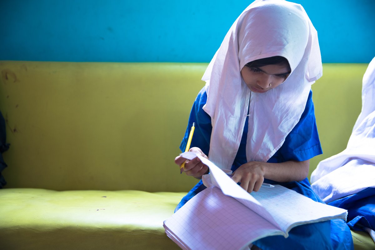 Image shows a young girl, who's wearing a white veil and blue school uniform, sitting on a bench. (c) Human Rights Watch
