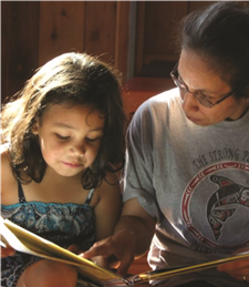 A photo of a Native American mother reading to her daughter.