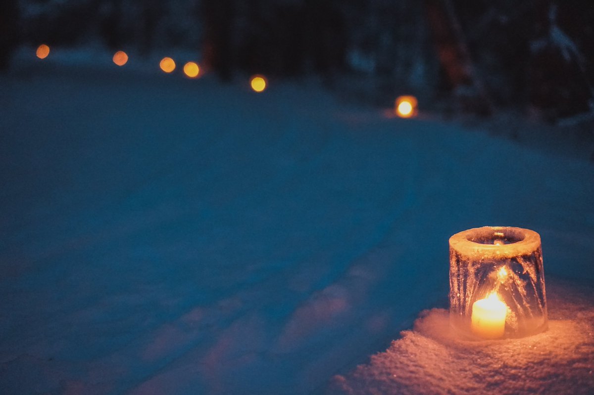 A line of luminaria light a snow covered trail at dusk