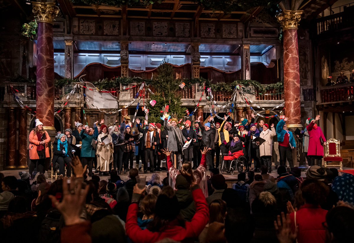 A group of carolers stand on the Globe Stage.