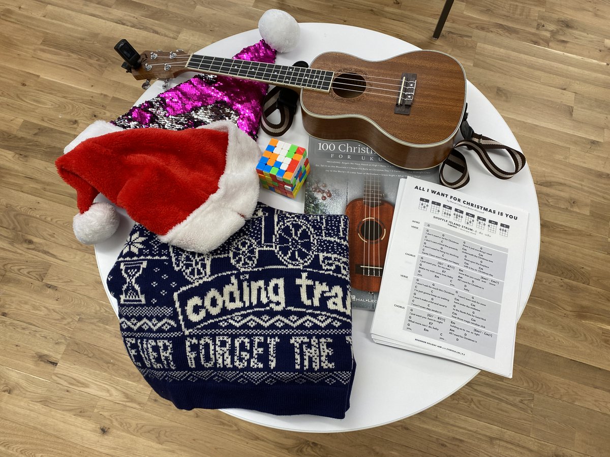 On a table: Coding Train sweater, santa hat, ukulele music, rubik's cube, and ukulele