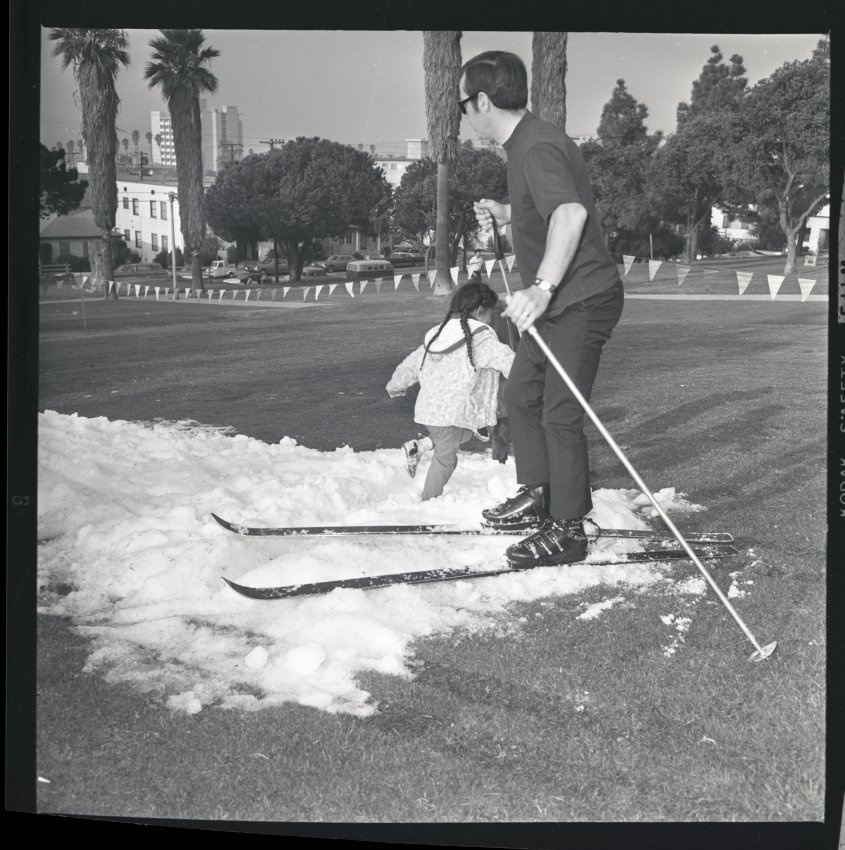 SMHistoryMuseum's tweet photo. A little girl plays next to a skier in artificial snow run at Hotchkiss Park. Two-acre Hotchkiss Park, originally the site of the Mooney Mansion, was given to Santa Monica in 1934. Photo dated 1969. ID: 3.2.10252 #FallbackFridays #WinterSolstice https://t.co/NN1Q5a5MTH https://t.co/Q44Ea2Xvid