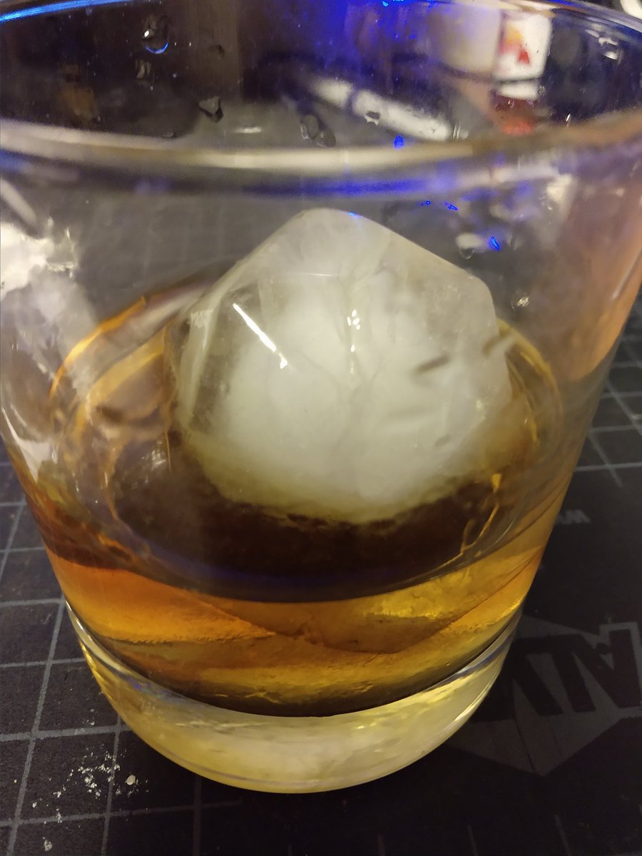 Glass of whiskey with a d20 ice cube