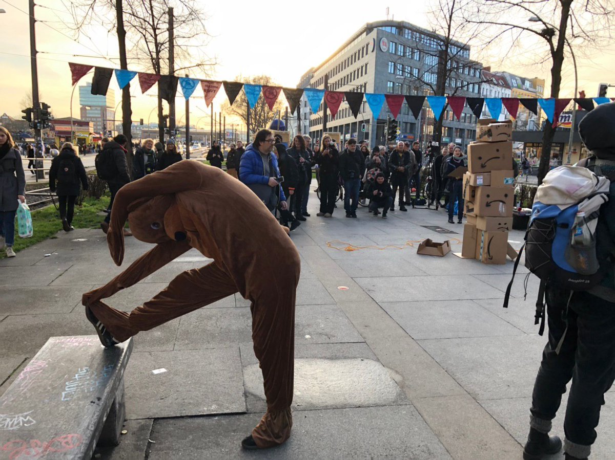 berlinvsamazon's tweet image. 100+Leute bei unserem ersten Aktionstag gegen den geplanten #amazon-Tower in #Berlin. Nachdem unser Bär den Turm aus Amazon-Paketen symbolisch umboxte🥊, posiert er nun mit Kundgebungsteilnehmer*innen und deren Messages gegen Amazon. 📢✊🏿👇🏽#BerlinVsAmazon #fightthetower