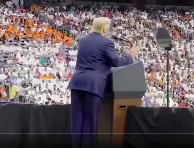 TomJChicago's tweet photo. Freeze frame from Trump's new video. Heavy podium lean &amp; the body brace contraption (many pics in this TL) protruding. It limits his jerking backwards. Note the jacket hem. A Men's Kaftan would be more comfortable &amp; functional at this point than these awkward business suits. https://t.co/xtsCOu1DYy