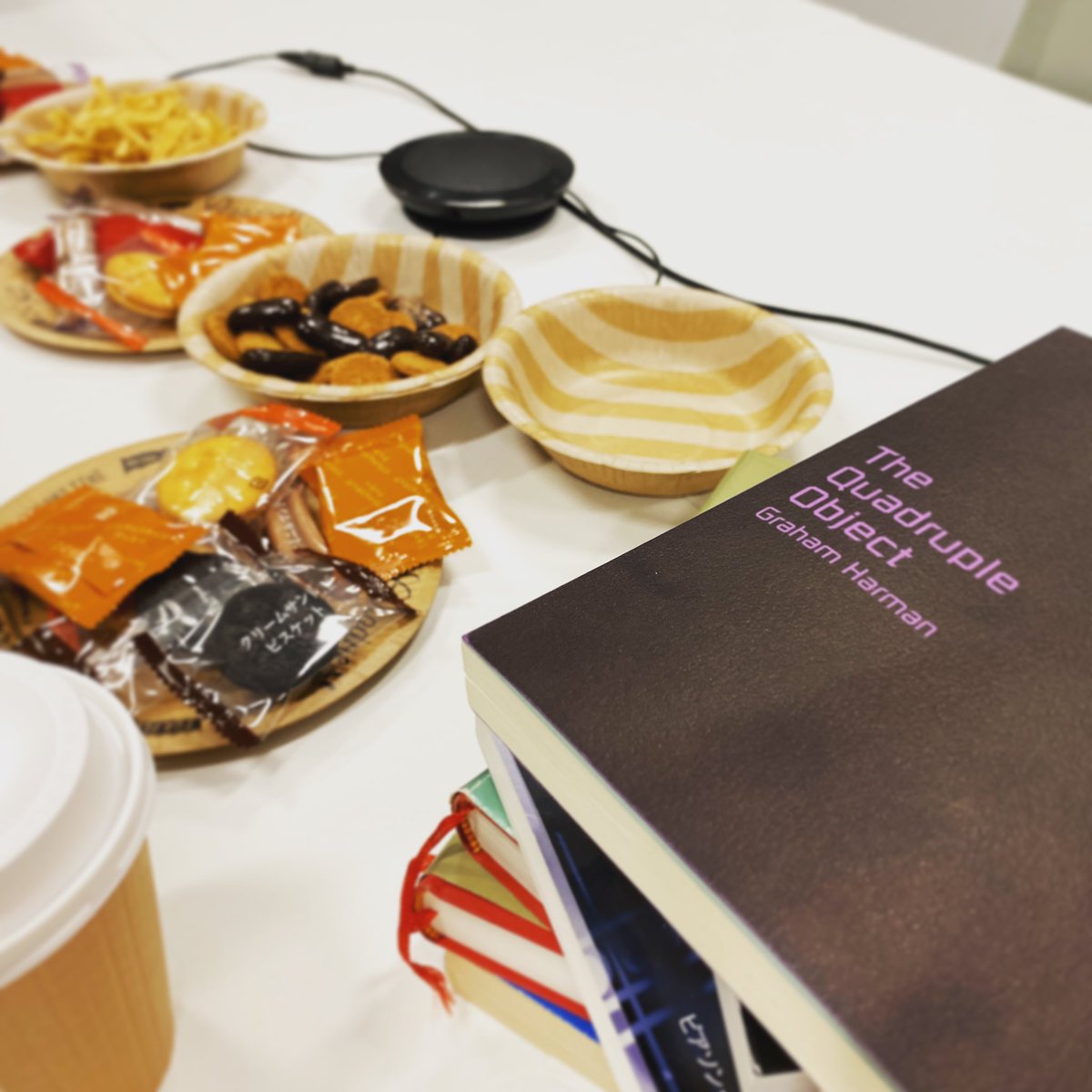 お菓子とコーヒーと山積みの本の写真です。