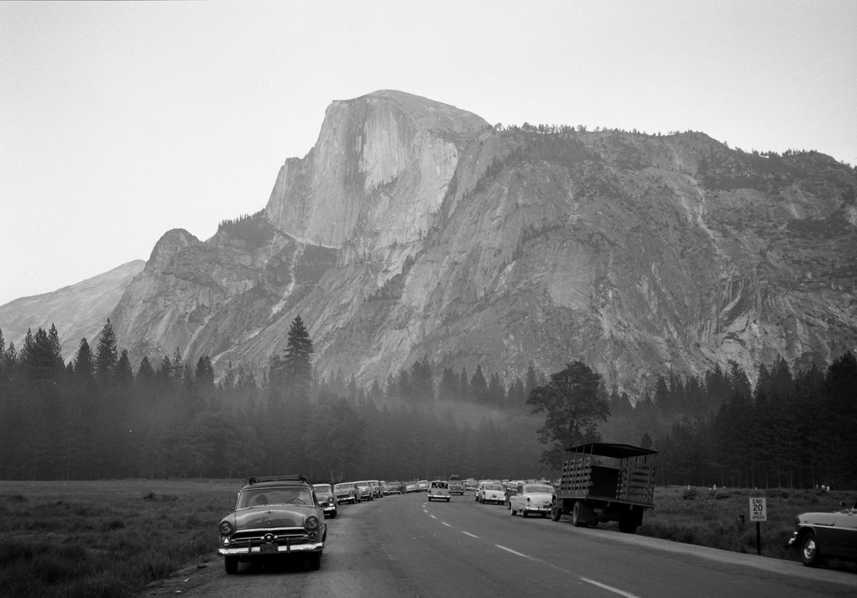 Stoneman Meadow and Half Dome in 1958. Vintage cars are parked along the road.