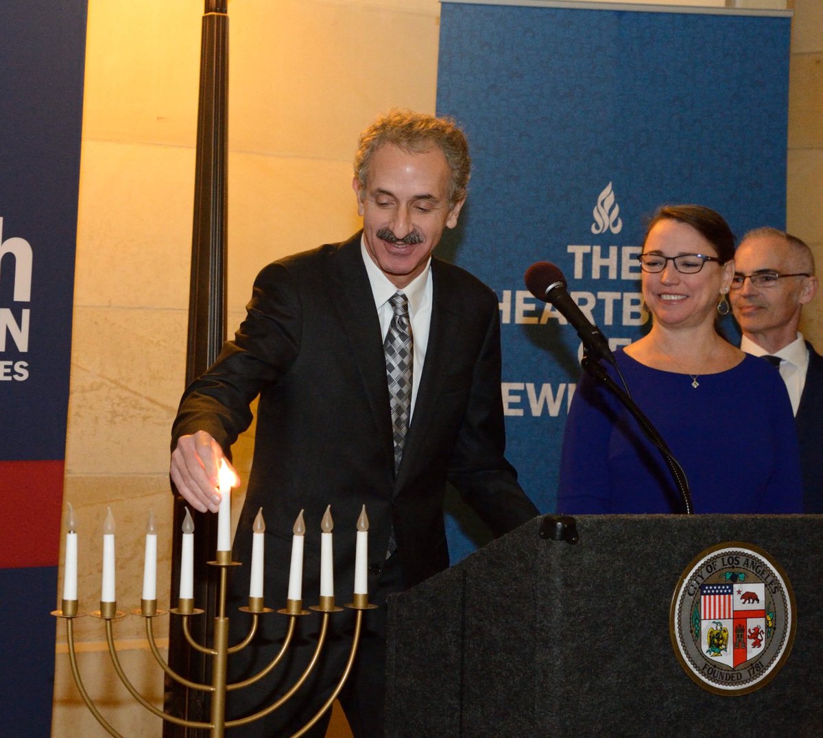 Man lights menorah at a Hanukkah party.