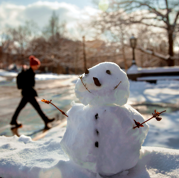 snowman sits on snow-covered ledge in front of Willard Straight Hall at Cornell University 