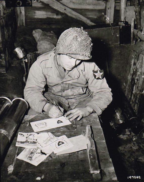 WarHistoryOL's tweet photo. Private Walter Prsybyla of the US 2nd Infantry Division writing Christmas cards for friends and family from an artillery ammunition storehouse, Heckhalenfeld, Germany, 30 November 1944. https://t.co/GXlwUNjJ8y
