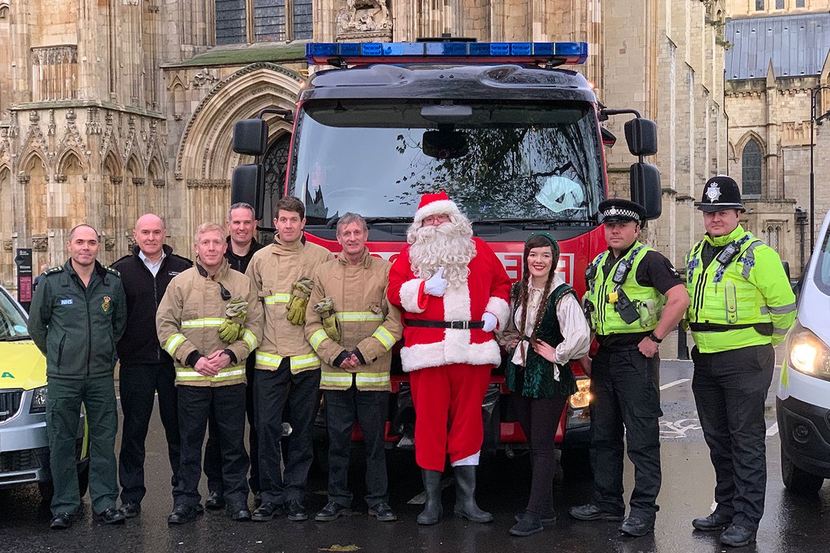 Santa claus in front of a fire engine with members of all emergency services.