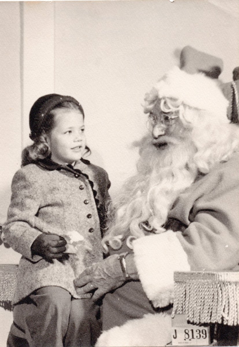 A young Elizabeth Warren takes a photo with Santa Claus, this time, looking happy and excited to see him.