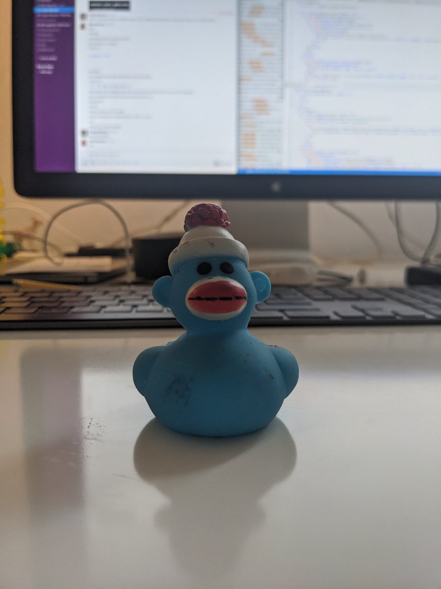 Rubber duck wearing a hat sitting in front of a computer