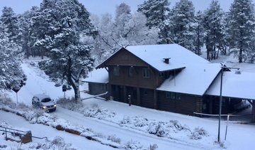 Description: a car driving past a rust railroad depot. Snow covers everything, including trees and the roadway.