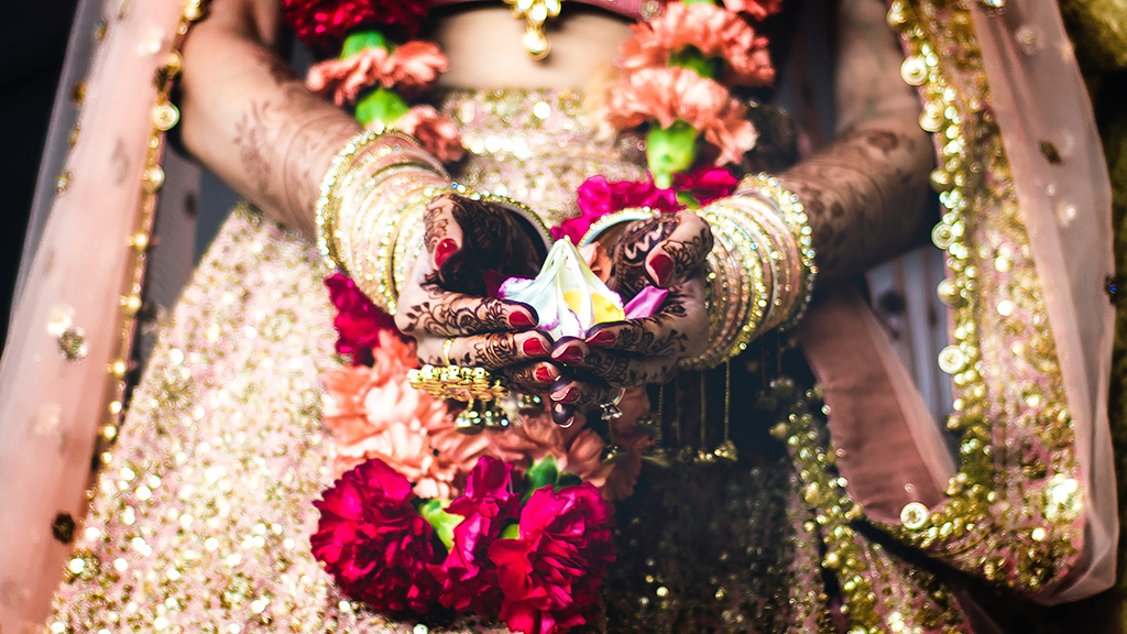 a photograph of a woman in an Indian wedding dress holding flowers