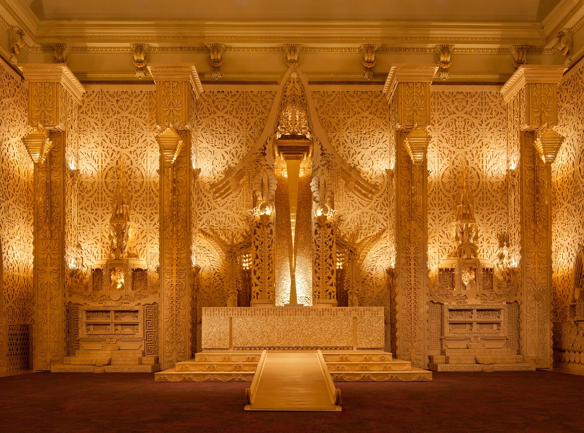 David Best “Temple” installation inside the Renwick Gallery Grand Salon of intricate wood patterned walls and an altar, lit with soft, warm lights. 