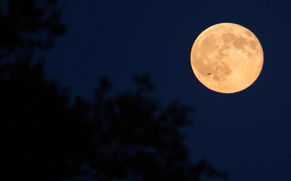 A plane is seen flying in front of the second full moon for the month of July, Friday, July 31, 2015 in Arlington, Va. In recent years, people have been using the name Blue Moon for the second of two full moons in a single calendar month. An older definition of Blue Moon is that it’s the third of four full moons in a single season. 