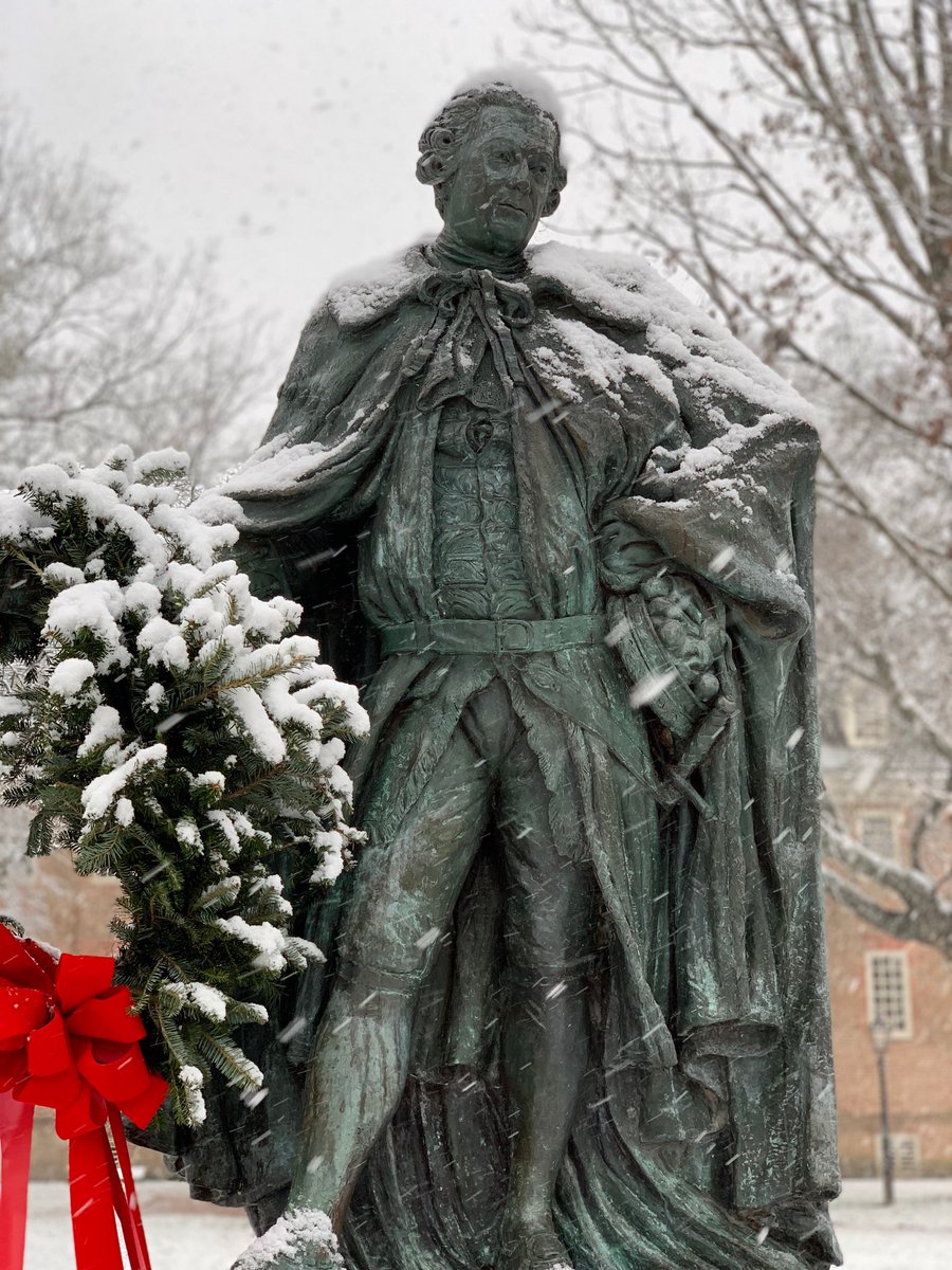 Lord Botetourt is covered in fresh snow and holds a holiday wreath with a red bow. 