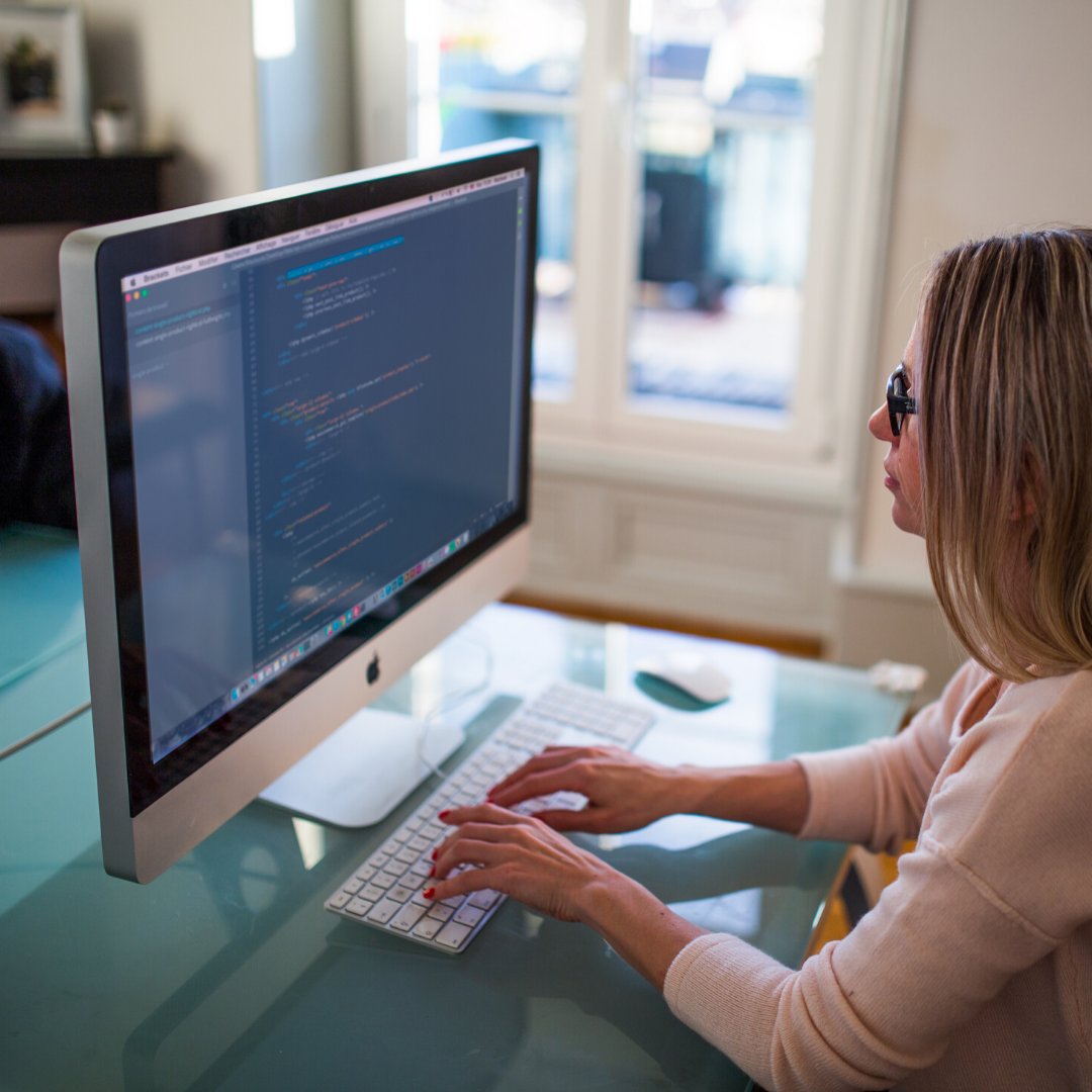 Woman seated at an office desk entering code into a website