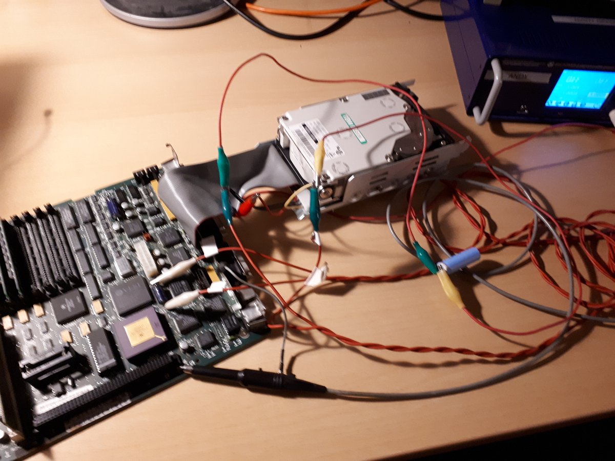 Bare logic board with hard drive and a bunch of cables connecting it to a lab power supply.