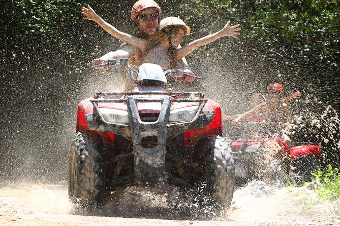 Father and daughter on ATV going through mud