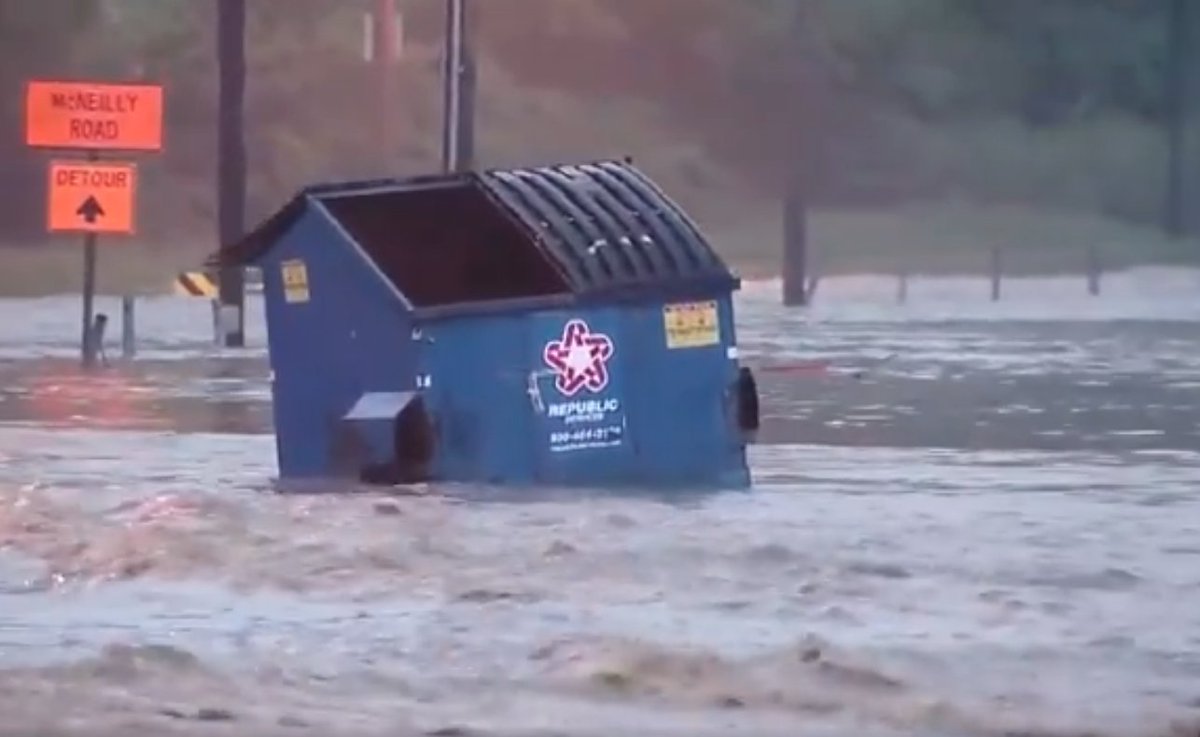 a floating dumpster caught in a pittsburgh flood current
