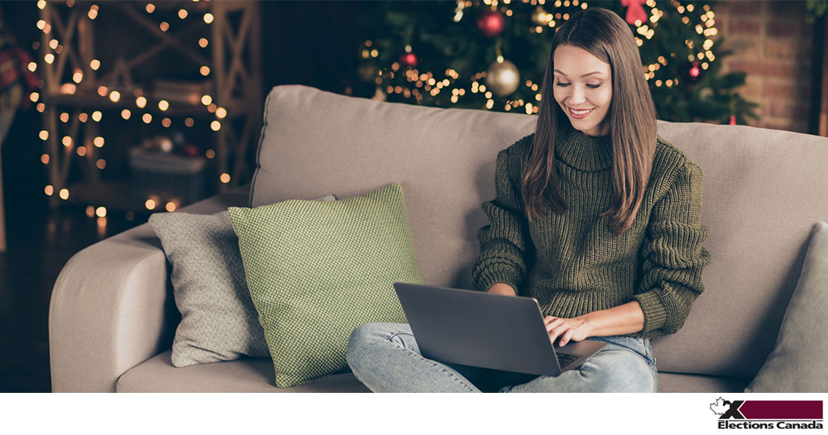 A woman sits on a couch looking at a laptop