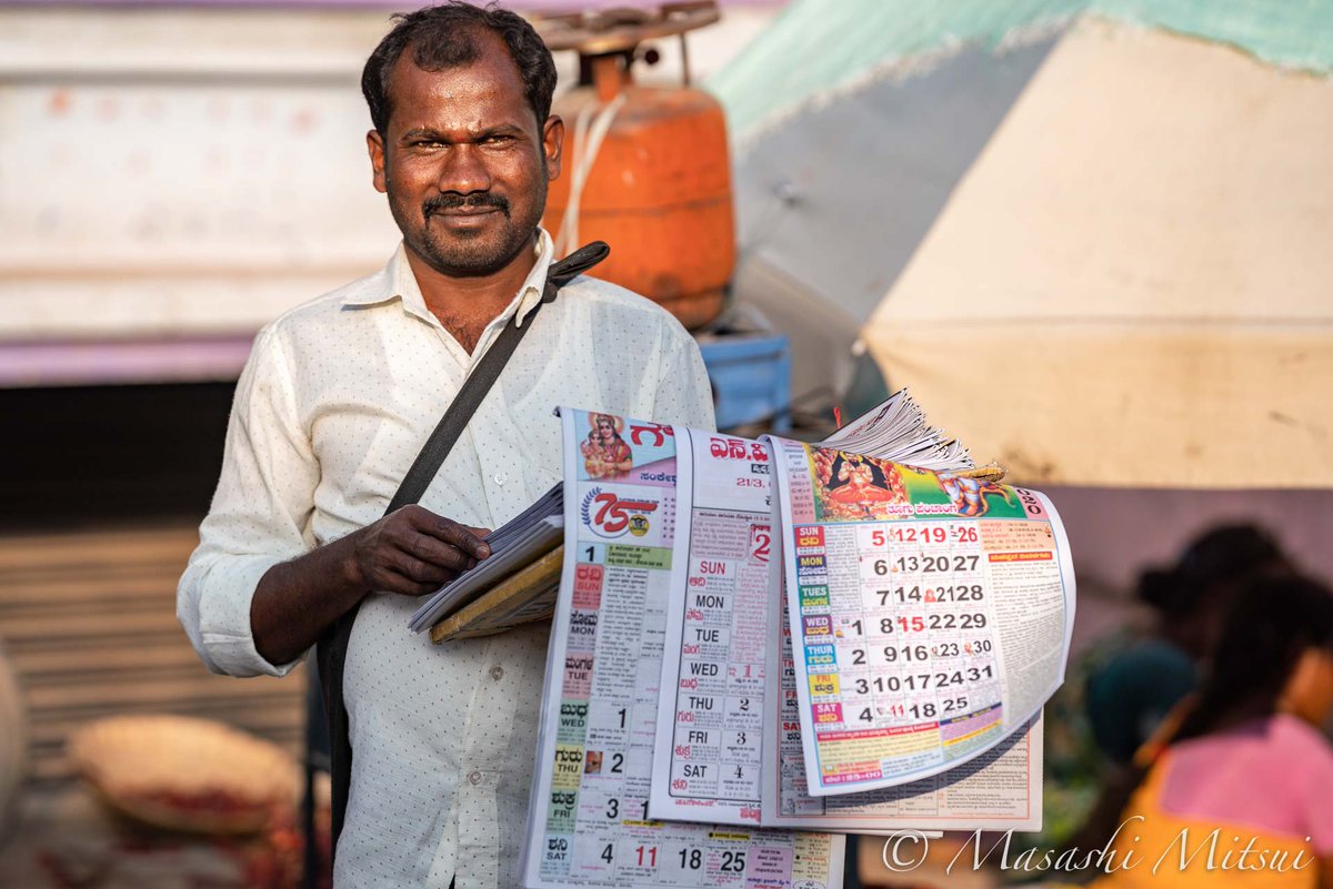 三井昌志 新年を迎えたインドの街角で 行商人が年度のカレンダーを売っていた インドのカレンダーって曜日が縦に並ぶ 縦書き が主流のようだ 横書きに慣れた目には ちょっと不思議な気がする