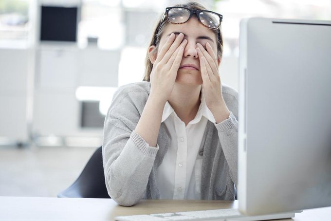 Woman sitting at computer rubbing eyes