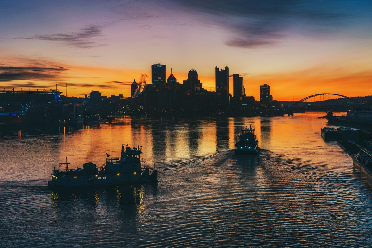 DaveDiCello's tweet photo. There's something calming about watching towboats on the rivers of #Pittsburgh at sunrise, with the boats &amp; city both silhouetted against a colorful sky. The ripples in the water add the perfect texture to the scene, with the skyline reflecting in the still water beyond the boats https://t.co/oXNmG3dTK4
