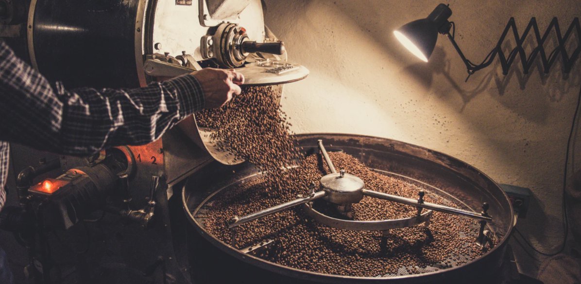 Large amount of coffee beans being poured into an industrial coffee grinder
