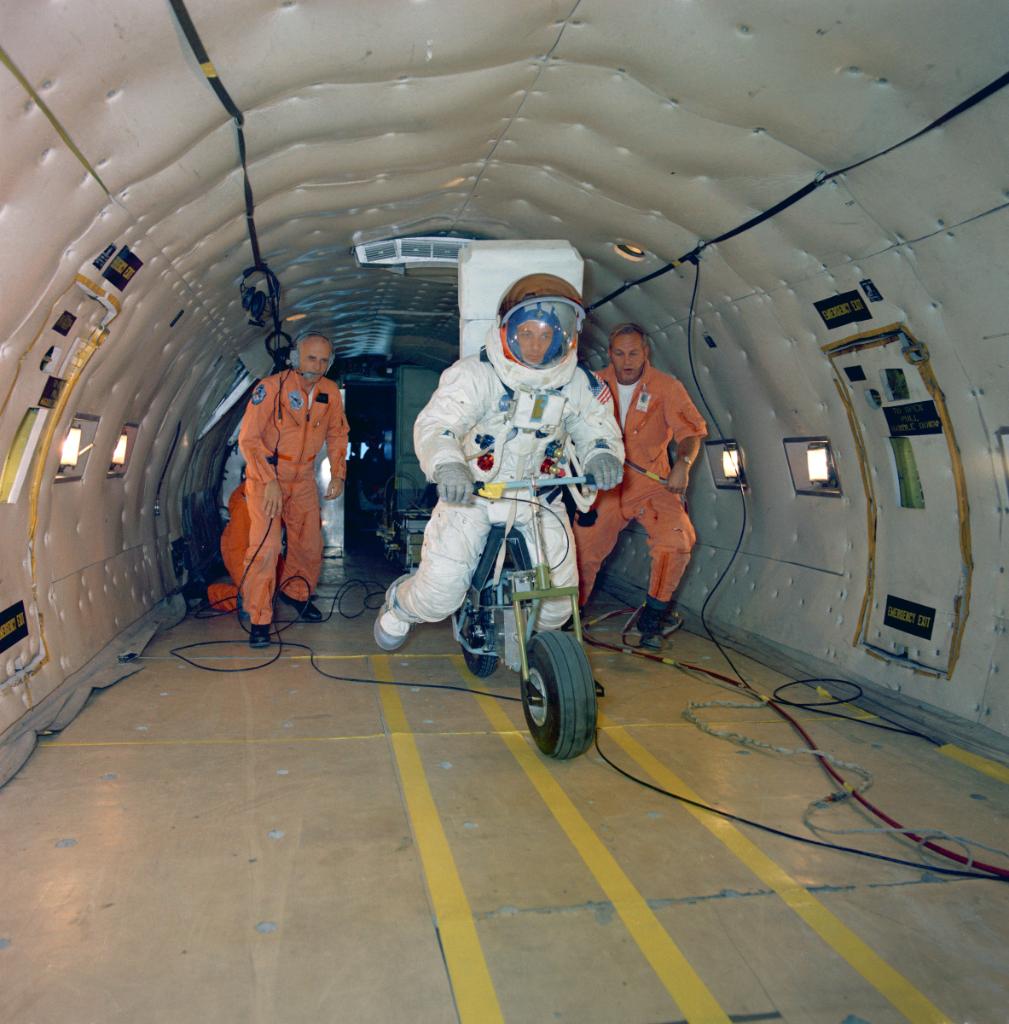 Electric Motor Scooter being tested by an astronaut in a full suit within the fuselage of a KC-135 aircraft. 