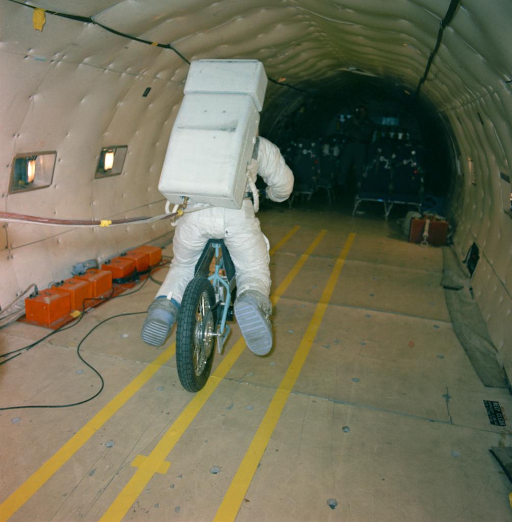 Electric Motor Scooter being tested by an astronaut in a full suit within the fuselage of a C-135 aircraft. 