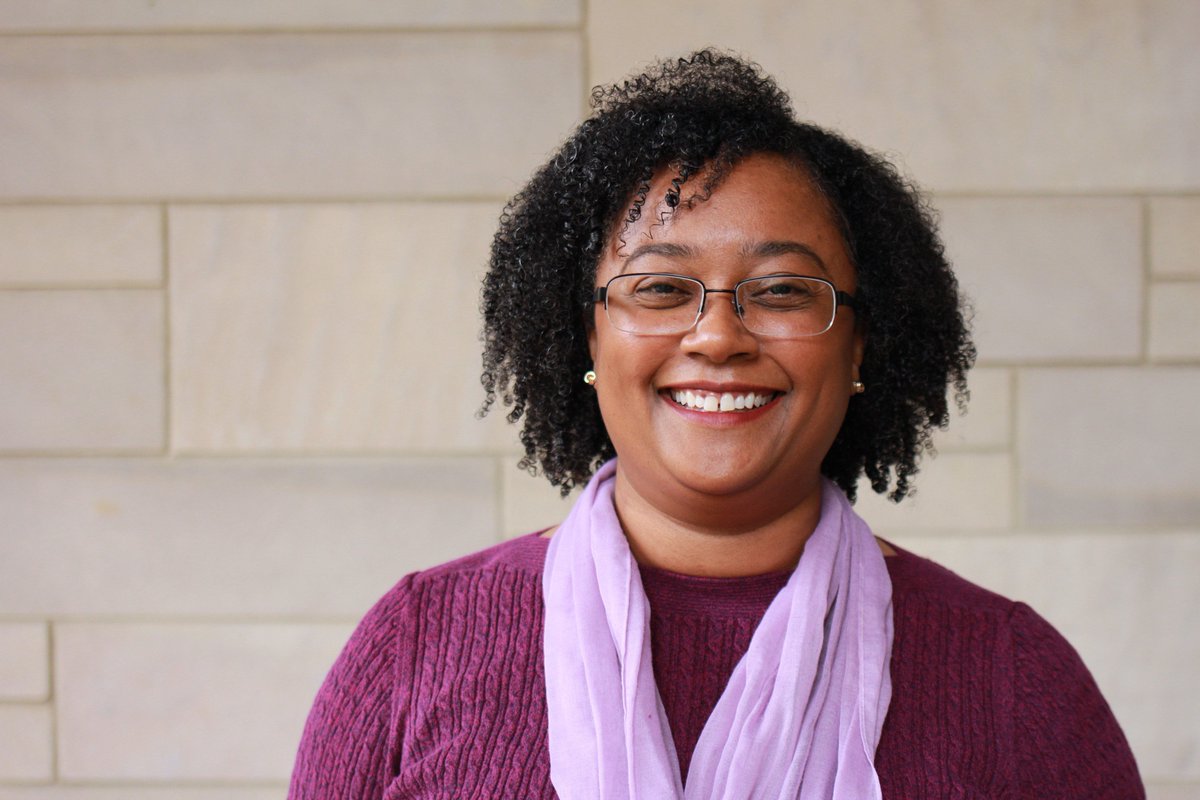 Dr. Sharlene Newman smiles while standing in front of a wall.