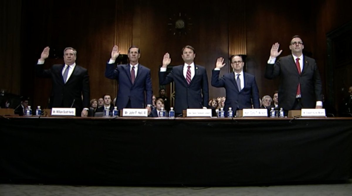 Five judicial nominees stand behind a table and take the oath before their confirmation hearing in the Senate Judiciary Committee. All five nominees in the image are white men.