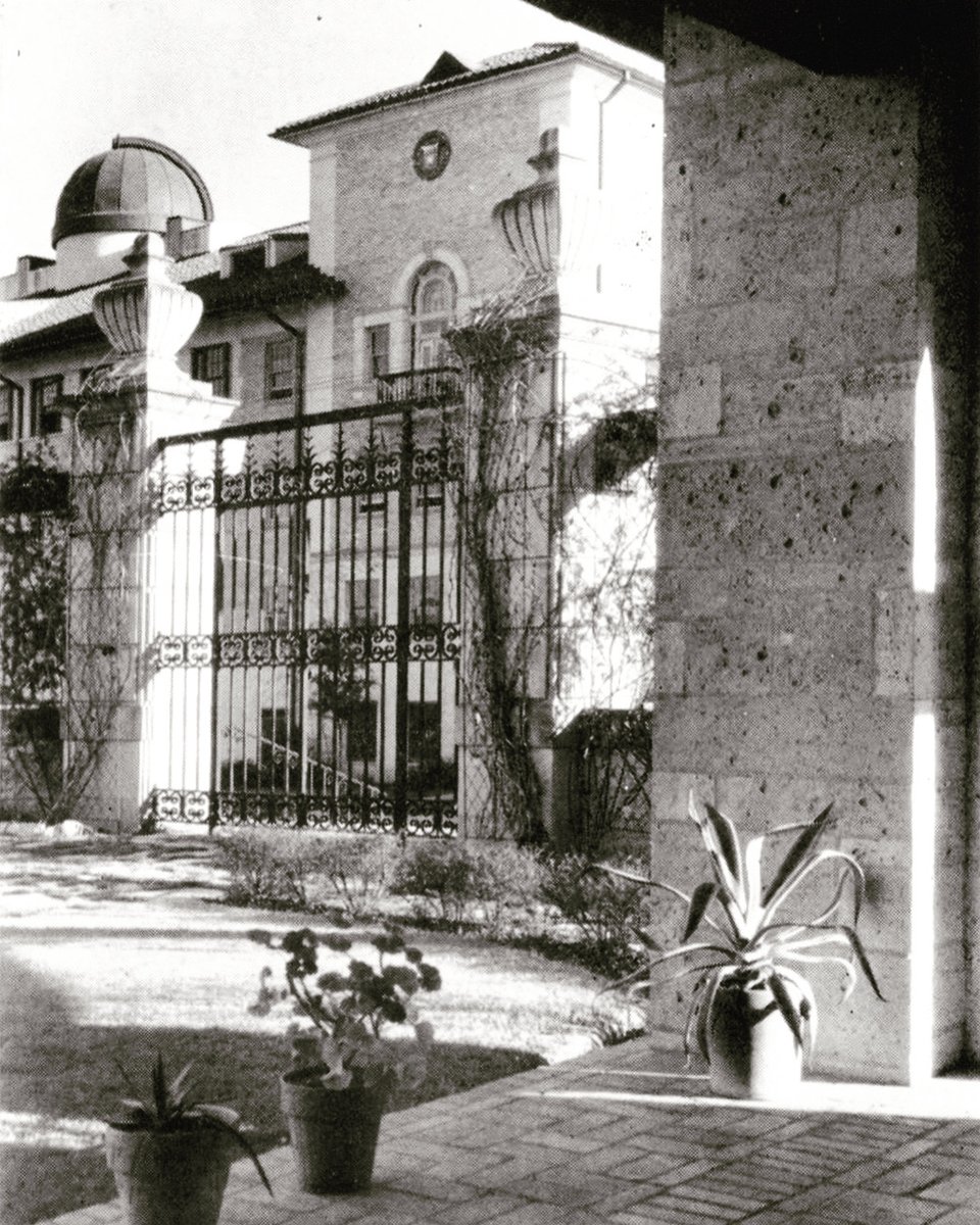 Painter Hall is seen through iron gates at the entrance of a courtyard patio in Mary E. Gearing Hall on the campus of The University of Texas at Austin in 1943.