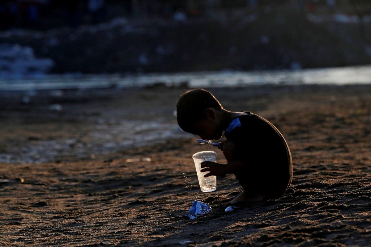 mxmqroo's tweet photo. El rostro mas duro de la migración. Un niño hondureño migrante se lava los dientes después de pasar la noche  en la orilla del río Suchiate a la espera del destino de la Caravana de Migrantes quienes fueron detenidos por la Guardia Nacional al intentar cruzar hacia México. https://t.co/QtesBquMXT