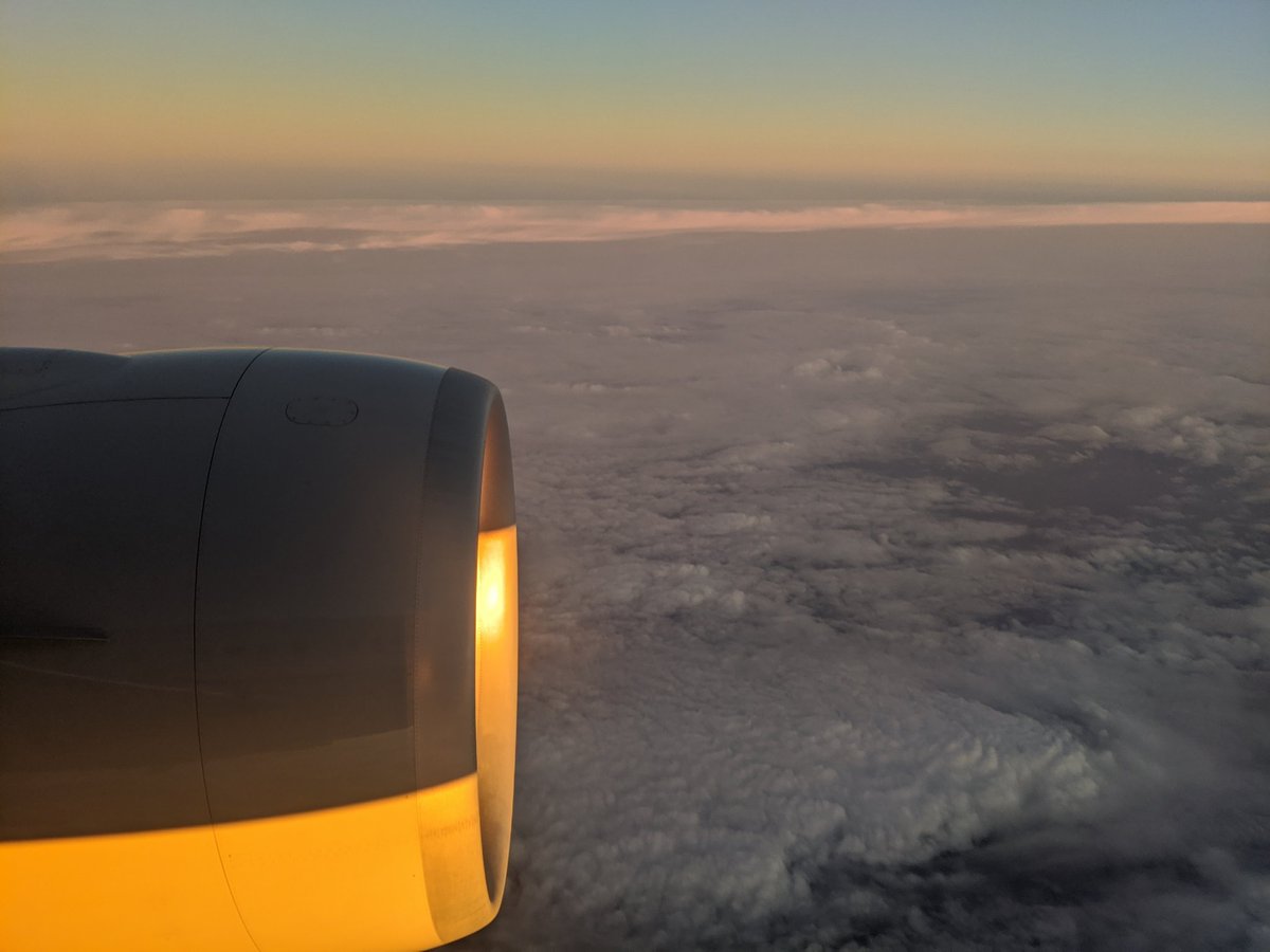 View from a plane window, the rising sun illuminating the engine