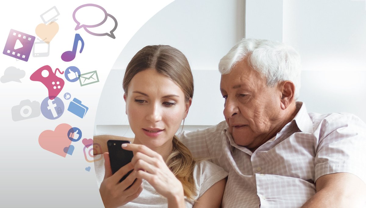 An older gentleman looks on as a younger woman explains phone apps.