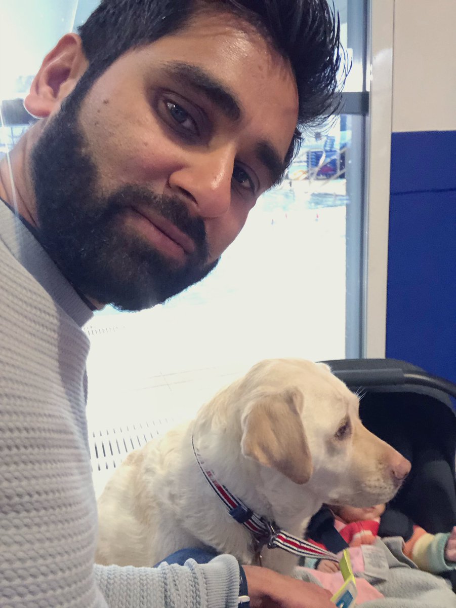 A selfie of a non-plussed looking Amit at the leisure centre (with the pool behind them but not very visible). Kika is next to him and the baby is in the car seat. Her face is not visible.