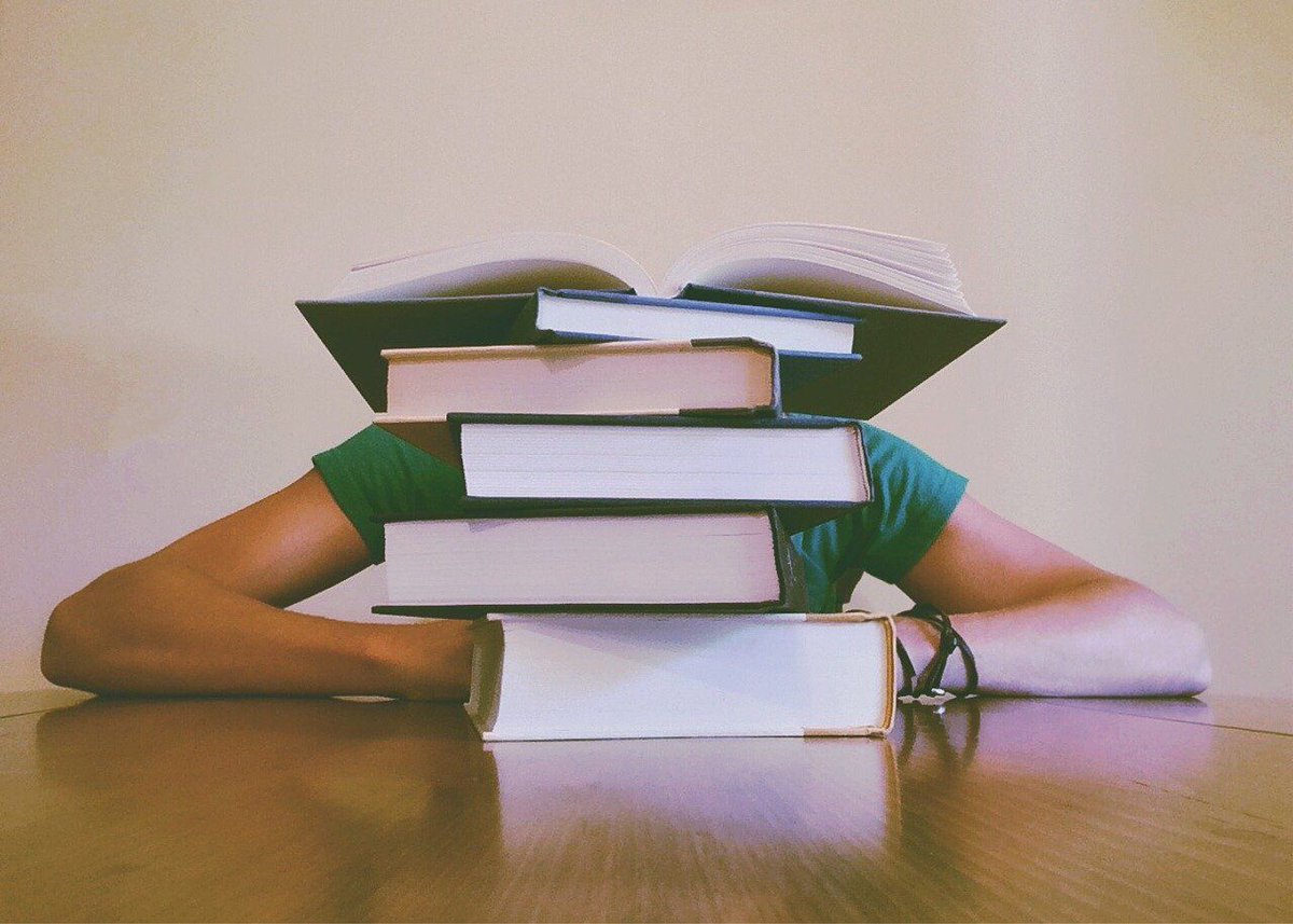 A student sitting behind a stack of books.