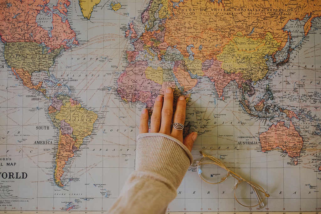 a woman's outstretched hand on top of a global wall map