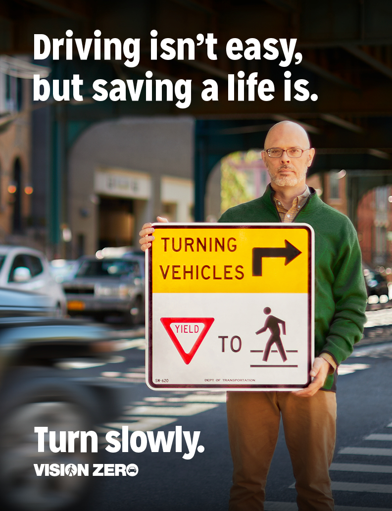 Person standing on sidewalk holding a traffic sign.