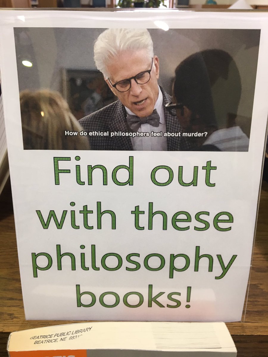 A sign with a screenshot from The Good Place of Michael saying “How do ethical philosophers feel about murder?” Beneath that in green it says “Find out with these philosophy books!”
