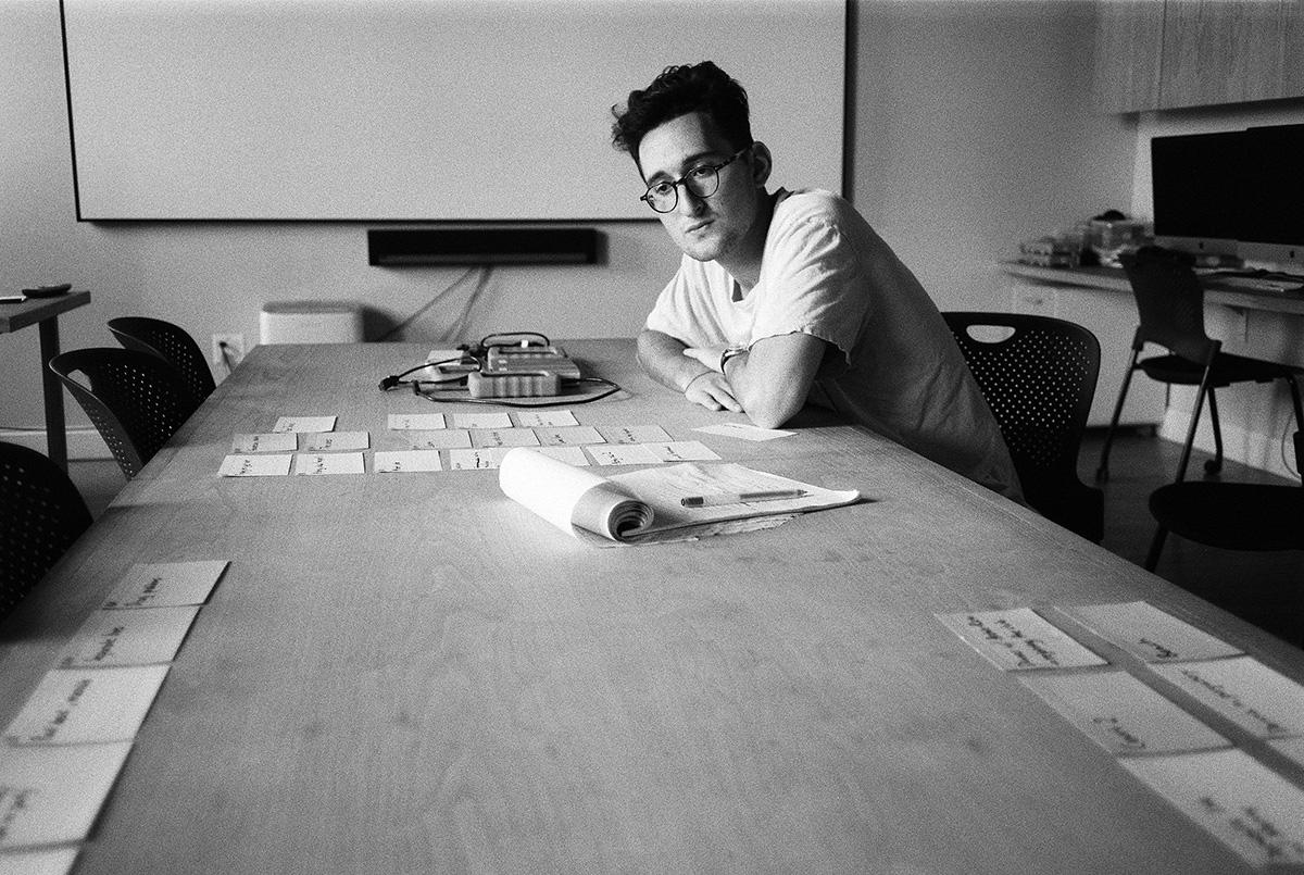 Lance sits at a table with cards and notes laid out before him 