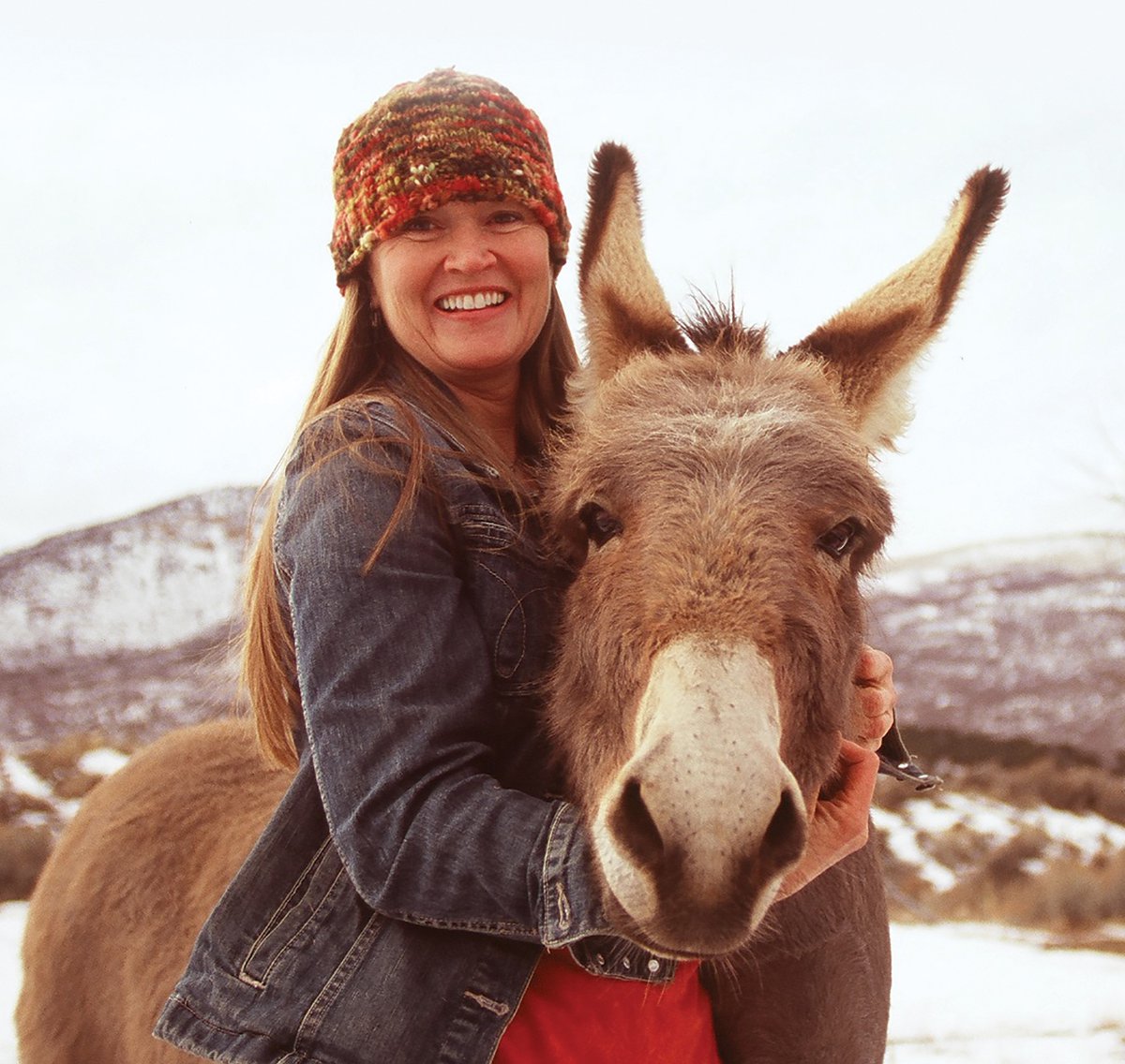 A woman hugs her burro around the neck